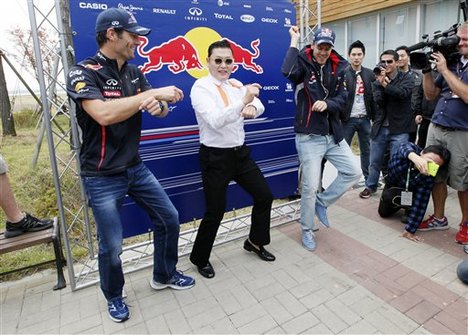 Red Bull driver Mark Webber, left, of Australia and his teammate Sebastian Vettel, right, of Germany perform with South Korean rapper PSY, centre, and his " Gangnam Style" dance before the Korean Formula One Grand Prix at the Korean International Circuit in Yeongam, South Korea, Sunday, Oct. 14, 2012.