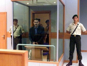 File - Kurdish rebel leader Abdulah Ocalan stands behind bulletproof and bombproof glass during his first trial in the prison island of Imrali on Monday, May 31, 1999.