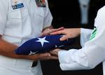 Capt. Kent D. Whalen, commanding officer of the Nimitz-class aircraft carrier USS Carl Vinson (CVN 70), is presented with the national ensign during a burial at sea ceremony for 22 former service members.