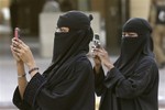 File - Women use their mobilephones to take pictures outside the Imam Turki bin Abdullah mosque as residents perform Eid al-Fitr morning prayers to mark the end of the holy fasting month of Ramadan Sunday, Aug. 19, 2012, in Riyadh, Saudi Arabia.