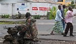 People walk past as M23 rebel soldier's take positions near the Heal Africa hospital in the center of Goma, Congo, Tuesday, Nov. 20, 2012.