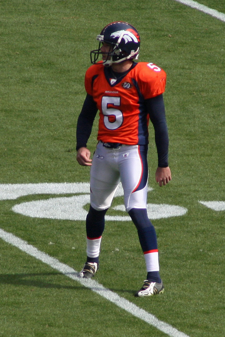 A Caucasian American football player dressed in full uniform practices before a game.