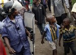 A Congolese policeman in riot gear keeps an eye on Goma residents including street children who gathered for an anti Kabila demonstration supported by the M23 rebel movement in Goma, eastern Congo, Wednesday Nov. 28, 2012.