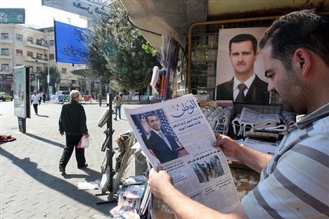 A Syrian man reads a newspaper covering Barack Obama's victory in the U.S. Presidential election as he stands in front of a picture of Syrian President Bashar Assad in Damascus, Syria, Wednesday, Nov. 5, 2008. In Syria, a nation isolated by the Bush administration in the last few years, the people and political analysts were hopeful Obama would work for peace in the Mideast and improve America's image and his win proved the failure of Bush's policies. Relations with Washington have started to improve recently but plummeted after a U.S. commando raid across the Iraq border into Syria killed eight people last m