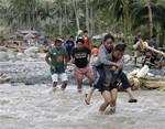 Residents cross a river in the flash flood-hit village of Andap, New Bataan township, Compostela Valley in southern Philippines Wednesday, Dec. 5, 2012.