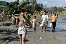 Residents walk back to an evacuation center after retrieving their household items in New Bataan township. Photo / AP