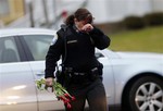 Newtown Police Officer Maryhelen McCarthy carries flowers near a memorial for shooting victims Sunday, Dec. 16, 2012 in Newtown, Conn.