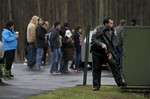 A police officer takes up a position behind the rectory of the St. Rose of Lima Roman Catholic Church in response to a bomb threat as onlookers watch from a Starbucks parking lot, Sunday, Dec. 16, 2012, in Newtown, Conn.