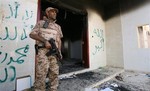 A Libyan military guard stands in front of one of the U.S. Consulate's burnt out buildings during the visit of President Mohammed el-Megarif, not shown, to the U.S. Consulate to express sympathy for the death of the American ambassador, Chris Stevens and his colleagues in the deadly attack on the Consulate last Tuesday September 11, in Benghazi, Libya, Friday, Sept. 14, 2012.