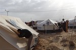 A Syrian refugee speaks to his family through a hole in their tent in Zaatari Syrian refugee camp, near the Syrian border in Mafraq, Jordan, Tuesday, Dec. 25, 2012.