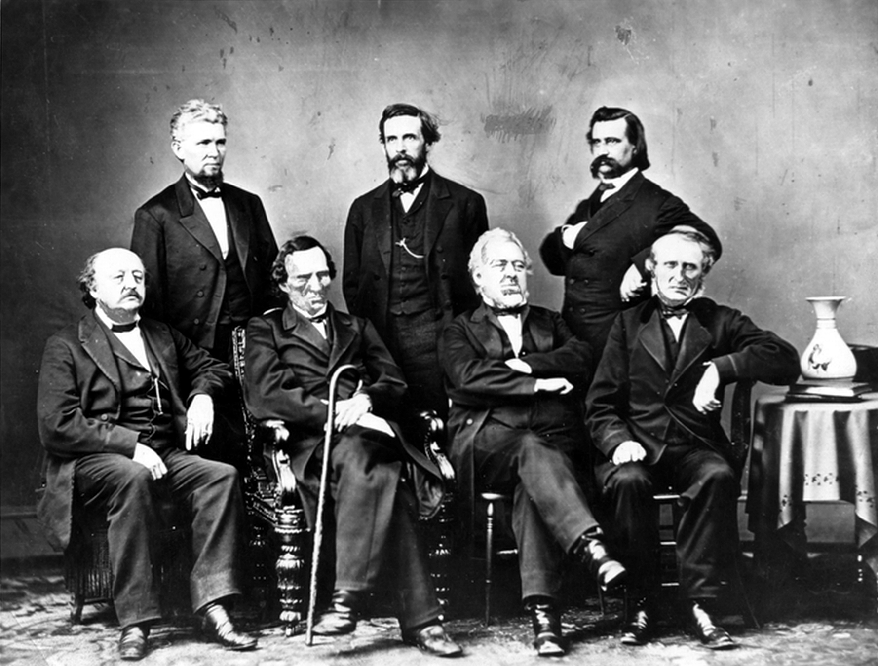 Seven men wearing suits posing for a group picture.