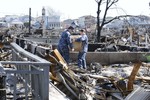 File - Electronics Technician 3rd Class Jackie McBride hands a box to Electronics Technician 2nd Class Shawn Cutter as they attempt to clear a street in Staten Island, New York that was leveled during Hurricane Sandy, Nov. 9, 2012.