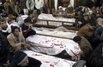 Pakistani Shiite Muslims sit next to the bodies of their relatives awaiting burial, who were killed in Thursday's deadly bombings, during a protest in Quetta, Pakistan, Saturday, Jan. 12, 2013.