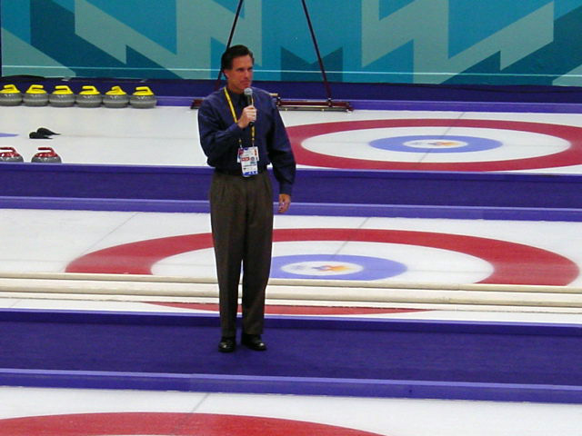 Photograph of Romney standing with microphone in middle of curling lanes