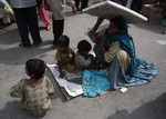 File - A beggar woman shielding her children from the sun in Srinagar, India, on July 09 2012.