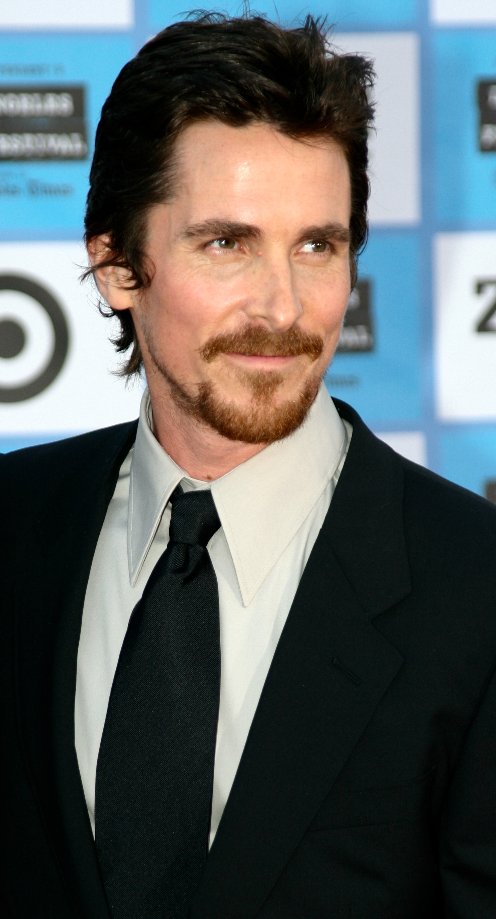 Christian Bale in a black suit at a movie premiere.