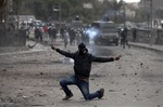 A masked Egyptian protester part of the Black Bloc, flashes the victory sign during clashes with riot police, background, near Tahrir Square, Cairo, Egypt, Monday, Jan. 28, 2013.