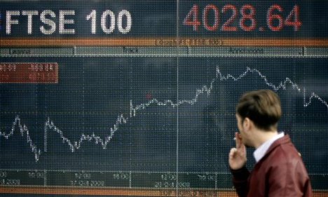 A pedestrian walks in front of a display showing the performance of Britain's FTSE 100 share index in London, Thursday, Oct. 23, 2008. European stock markets are lower following hefty losses in Asia earlier and an expected further retreat on Wall Street as spreading pessimism over corporate earnings reinforces concerns about the world e