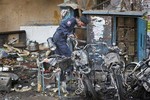 An official of India's National Investigation Agency looks for evidence in the debris at one of the two bomb blast sites, in Hyderabad, India, Friday, Feb. 22, 2013.