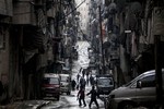 In this Tuesday, Dec. 4, 2012 file photo, Syrians walk past damaged homes during heavy fighting between Free Syrian Army fighters and government forces in Aleppo, Syria.