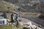 UN officers, one using binoculars, look towards Syria as they stand along the border between Majdal Shams in the Golan Heights, and Syria, as security is tightened ahead of Land Day,Friday, March 30, 2012.