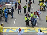 Medical workers wheel the injured across the finish line during the 2013 Boston Marathon following an explosion in Boston, Monday, April 15, 2013.