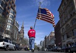 Lt. Mike Murphy of the Newton, Mass., fire dept., carries an American flag down the middle of Boylston Street after observing a moment of silence in honor of the victims of the bombing at the Boston Marathon near the race finish line, Monday, April 22, 2013, in Boston, Mass.