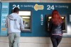A man and a woman withdraw money from Cyprus ATMs