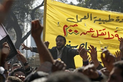 Public transportation workers protest in demand of salary raises in front of the national TV building, right, in Cairo, Egypt, Monday Feb. 14, 2011. Thousands of Egyptian state employees, protested Monday in Cairo to demand better pay and conditions in a wave of labor unrest unleashed by the uprising that ousted President Hosni Mubarak.