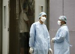 Workers wearing masks stand outside a side entrance to a hotel used to quarantine students from the Nanhu Zhongyuan Primary School in Beijing, China, Sunday, July 5, 2009.