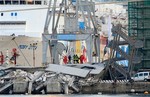 Rescue personnel stand on rubble next to a tilted staircase, part of a control tower which collapsed after a cargo ship slammed into it during a shift change Tuesday night in the port of Genoa, northern Italy, killing at least three people, Wednesday, May 8, 2013.