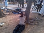 In this photo taken with a mobile phone, Tuesday, May. 7, 2013, Bakura Ibrahim, a suspected member of Islamic extremist group arrested by soldiers is tied to a tree in Bama, Nigeria.