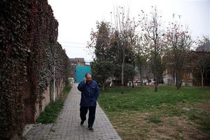 Chinese dissident artist Ai Weiwei talks on his mobile phone in a courtyard at home in Beijing, China, Tuesday, Nov. 8, 2011. Thousands of people have sent more than $800,000 to Ai, some tossing cash folded into airplanes over his gate, to help him pay a tax bill they see as government harassment, he said Monday. (AP Photo/Ng Han Guan)