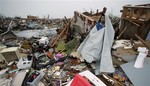 Victor Gonzalez seeks shelter from the rain under a sheet of plastic as he helps a friend salvage items from a tornado-ravaged home Tuesday, May 21, 2013, in Moore, Okla.