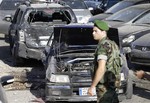 A Lebanese army soldier stands guard in front of damaged cars where a rocket struck a car exhibit at the Mar Mikhael district, south of Beirut, Lebanon, Sunday May 26, 2013.