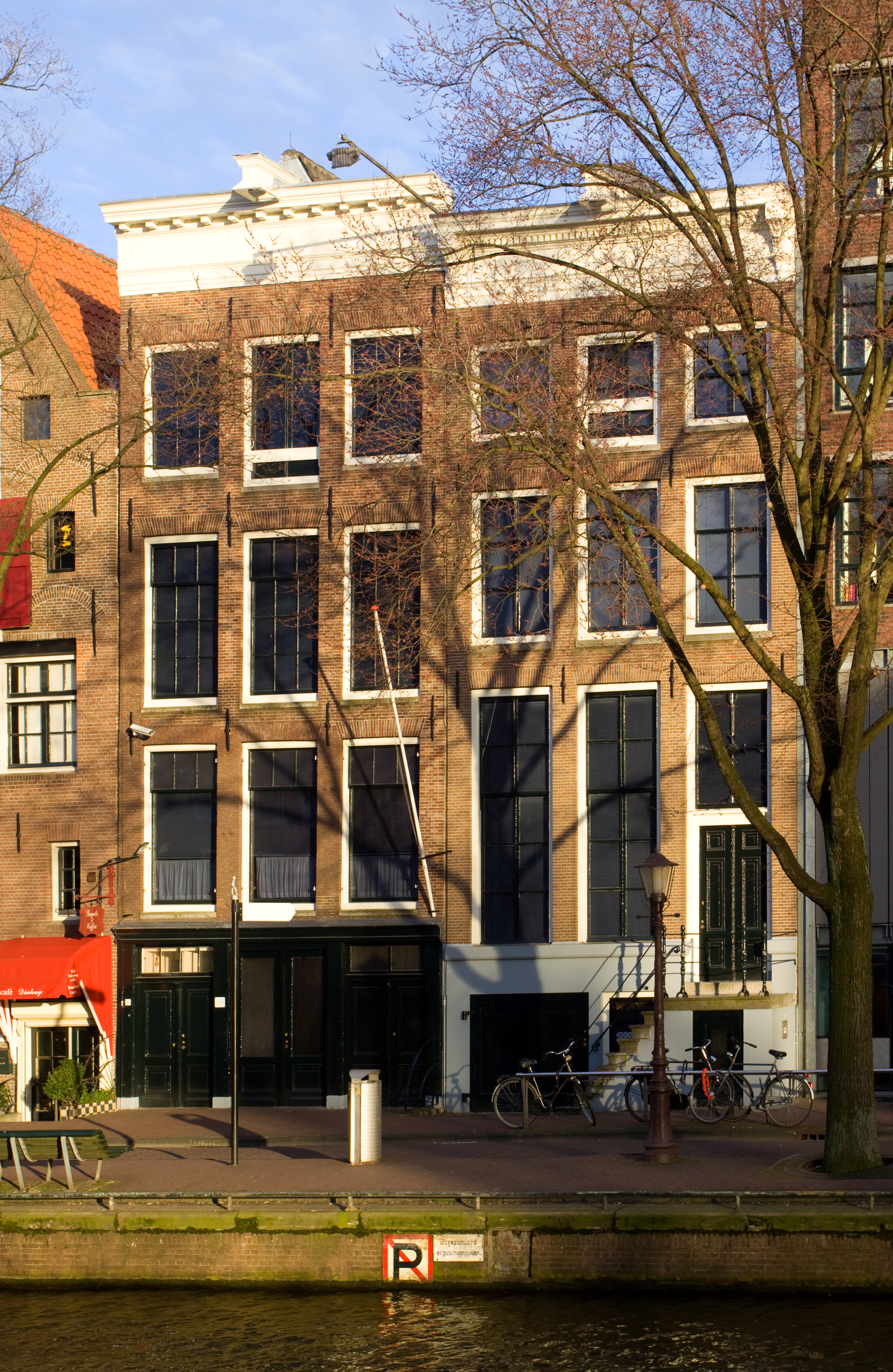 A photograph taken from the opposite side of the canal shows two four story buildings which housed the Opekta offices and behind them, the Secret Annexe