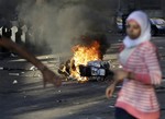 An Egyptian woman runs past a burning scooter that was set on fire during clashes between opponents and supporters of ousted President Mohammed Morsi, in Cairo, Egypt, Monday, July 22, 2013.