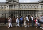 People queue to look at a notice proclaiming the birth of a baby boy of Prince William and Kate, Duchess of Cambridge on display for the public view at Buckingham Palace in London, Tuesday, July 23, 2013.