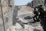 Syrian army personnel shoot towards rebel fighters during a tour for journalists organized by the Syrian Information Ministry in the Damascus suburb of Jobar, Syria, Sunday, July 14, 2013.