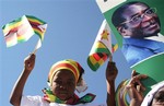 Supporters gather at the Harare airport Friday July 4, 2008 to welcome Zimbabwean President Robert Mugabe, portrait on placard, on his return to Harare from Egypt, where he attended the African Union summit.