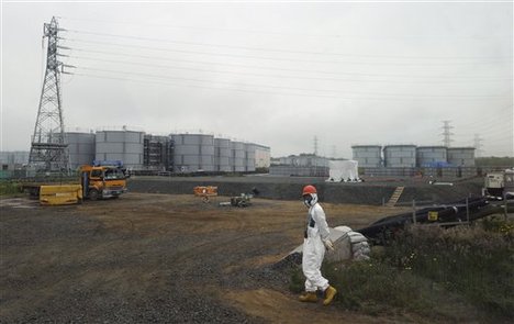 In this Wednesday, June 12, 2013 photo, a construction worker walks beside the underground water tank and water tanks at the Fukushima Dai-ichi nuclear plant at Okuma in Fukushima prefecture, Japan.