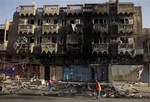 People clean up the aftermath of a car bomb attack on a convenience store in the Shaab neighborhood of Baghdad, Iraq, Sunday, Aug. 11, 2013.