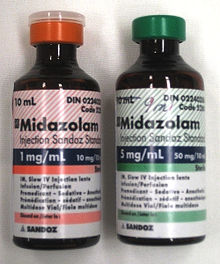 Two 10 ml bottles labeled Midazolam  - the bottle on the left has a label in red and says 1 mg/ml; the one on the right is in green and says 5 mg/ml. Both bottles have much fine print.