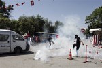 Tunisian opposition politician Mohammed Brahmi's supporters run in the tear gas during clashes with police after the funerals in Tunis, Saturday July, 27, 2013.