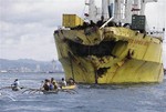 Volunteers search near the bow-damaged cargo ship Sulpicio Express Siete Saturday Aug. 17, 2013, a day after it collided with a passenger ferry off the waters of Talisay city, Cebu province in central Philippines.