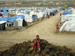 File - In this Friday, Feb. 15, 2013 photo, a Syrian Kurdish refugee plays on a pile of dirt in the Dumiz refugee camp in northern Iraq.