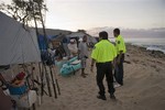 Hawaii Department of Emergency Management officers warn homeless campers of the tsunami warning on Maile Beach, Saturday, Feb. 27, 2010, in Waianae, Hawaii.