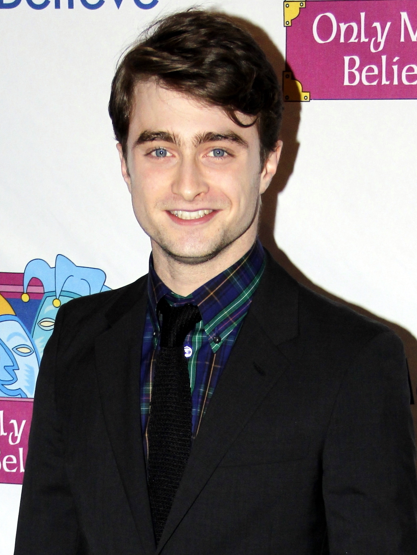 A male in his early twenties with brown hair and blue eyes is smiling at the camera.