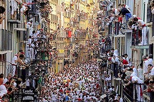 People standing on balconies look at participants as they run in front of Alcurrucen's bulls during the first bull run of the San Fermin Festival.