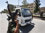 A Syrian army soldier secures the scene as he stands next to a military truck which was attacked by a roadside bomb, in Daraa city, southern Syria, on Wednesday May 9, 2012.